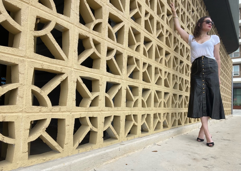 a woman in a Roberto Cavalli leather skirt with gold buttons, a white tee shirts and black sandal pumps