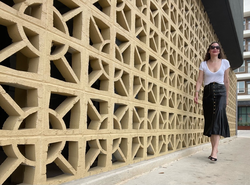 a woman in a white tee and a Roberto cavalli leather skirt with gold buttons and black pumps 