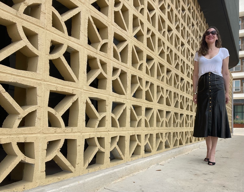 a woman in a Roberto Cavalli leather skirt with gold buttons, a white tee shirts and black sandal pumps