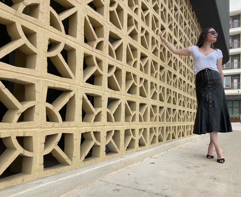 a woman in a Roberto Cavalli leather skirt with gold buttons, a white tee shirts and black sandal pumps