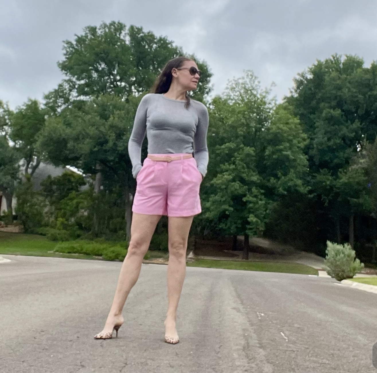 a woman in pink linen shorts with a grey long sleeve sweater and leopard print mules