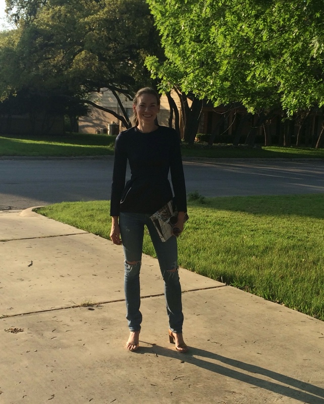 a woman in a navy peplum blouse and distressed jeans and metallic heels