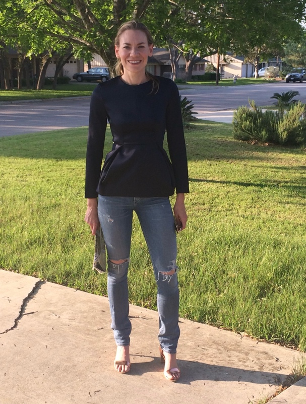 a woman in a navy peplum top and distressed jeans with metallic heels and a painted clutch