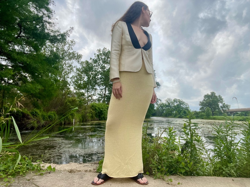 a woman in a yellow maxi knit skirt, a white with black lapel tux blazer and black thong sandals