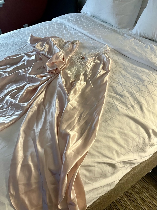 a pink peignoir set on a white bed