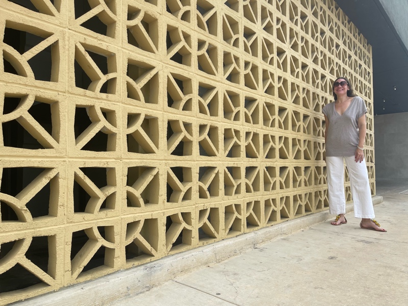 a woman in white jeans and a sweater vest with raffia sandals 