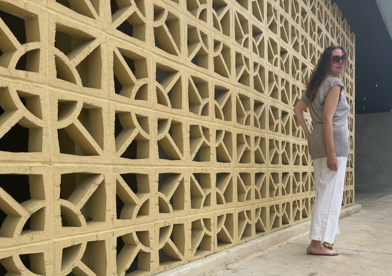 a woman in white jeans and a sweater vest with raffia sandlas