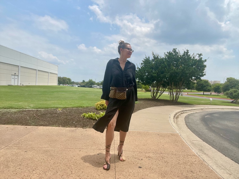 a woman in a black linen shirt dress, a Gucci belt bag and lace up asymmetrical shoes