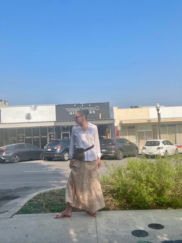 a woman in a white button down, a leopard print linen skirt, a Gucci belt bag and lace up sandals