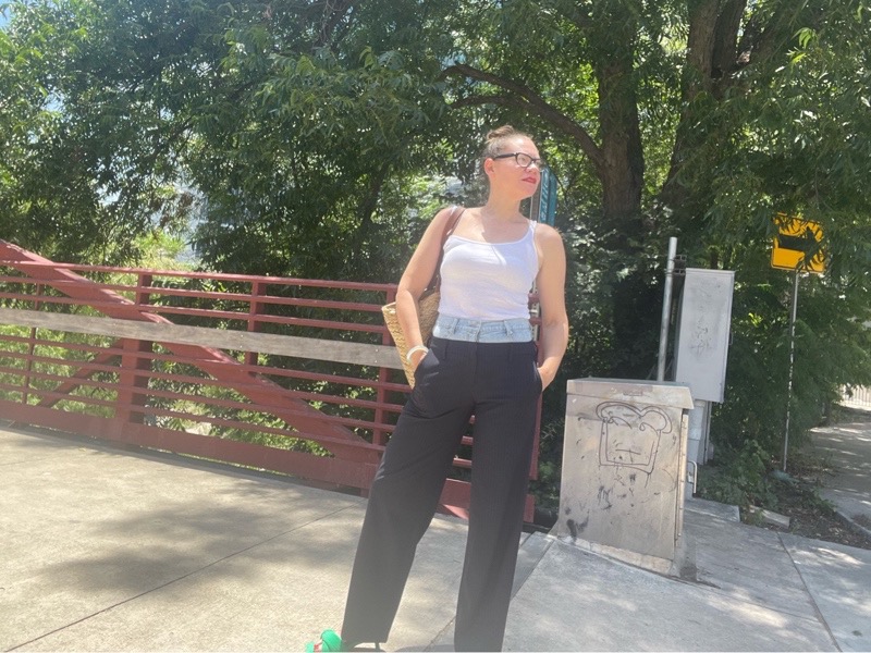  woman in a combo pinstripes pant and denim waist with a white tank and green mules