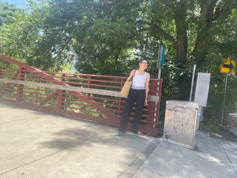  woman in a combo pinstripes pant and denim waist with a white tank and green mules
