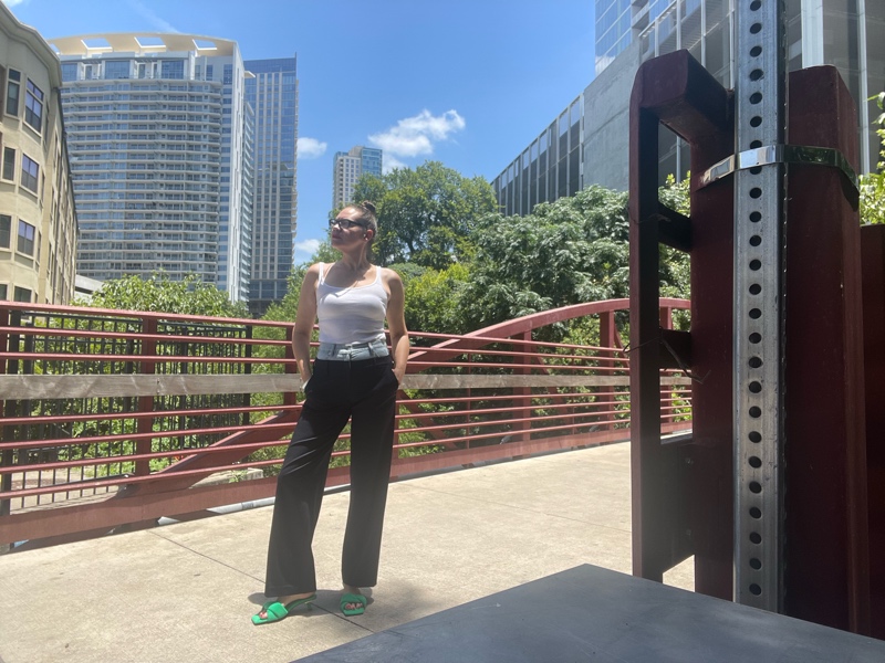 a woman in a combo pinstripes pant and denim waist with a white tank and green mules
