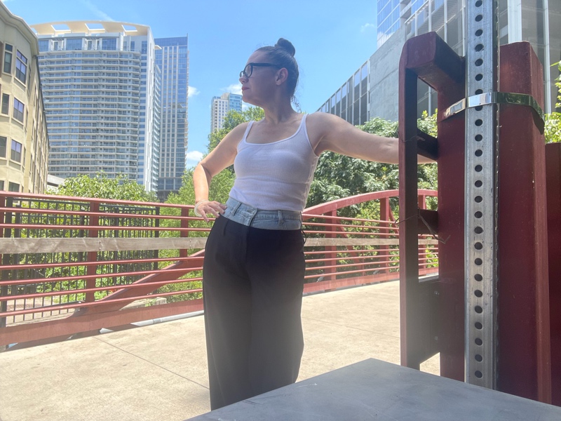  woman in a combo pinstripes pant and denim waist with a white tank and green mules