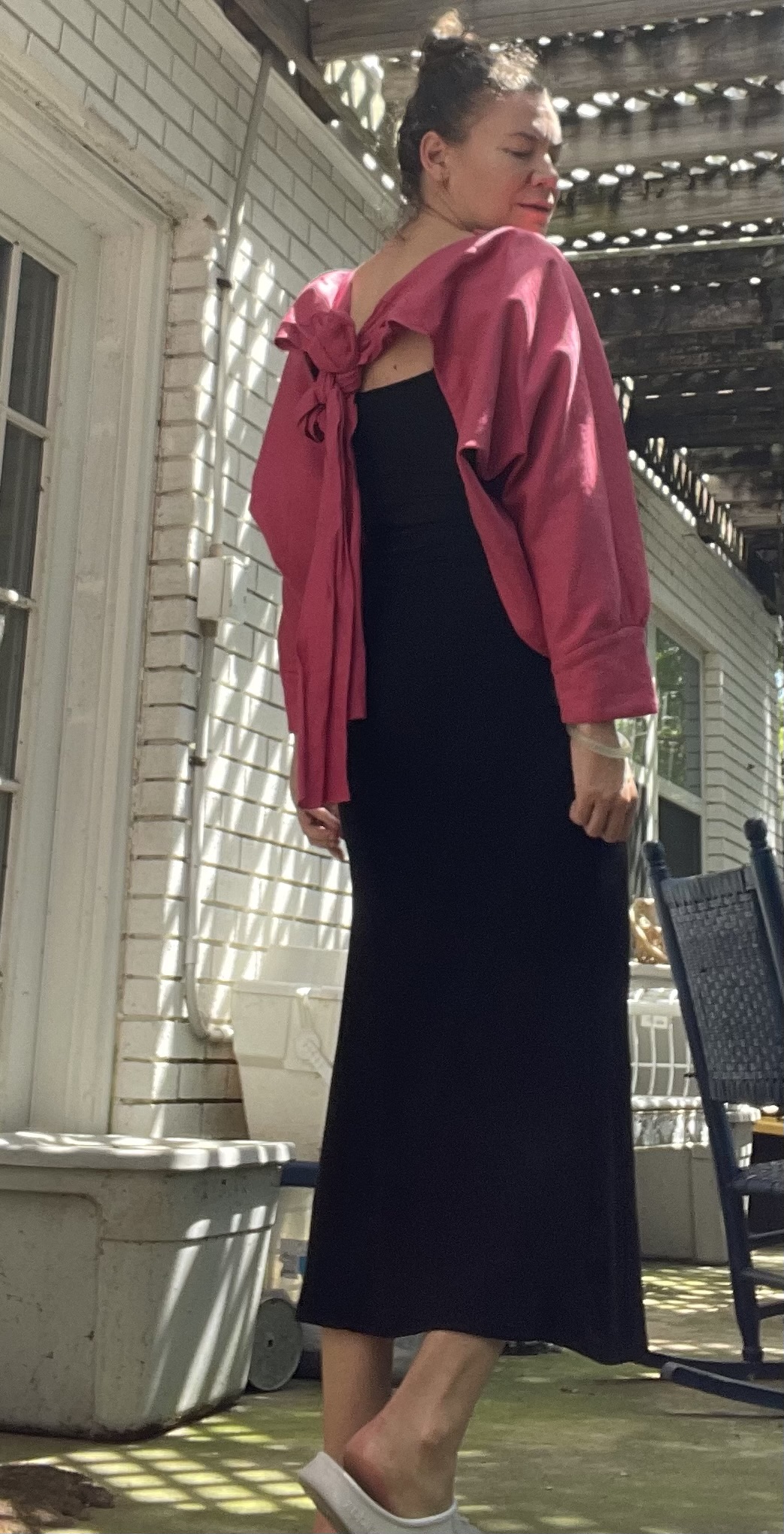 a woman in a black maxi dress with a pink bolero over and white and black clogs