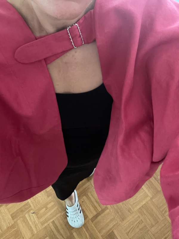 a woman in black maxi dress and a pink bolero and white and black clogs