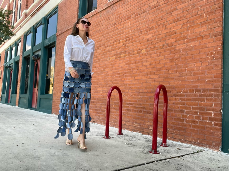 a woman in a denim skirt made of circle, a white button down and a nude heel