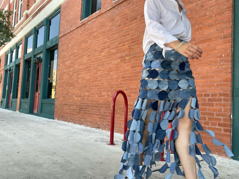 a woman in a denim skirt made of circle, a white button down and a nude heel