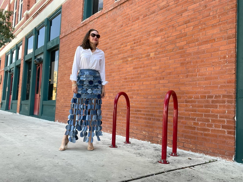 a woman in a denim skirt made of circle, a white button down and a nude heel
