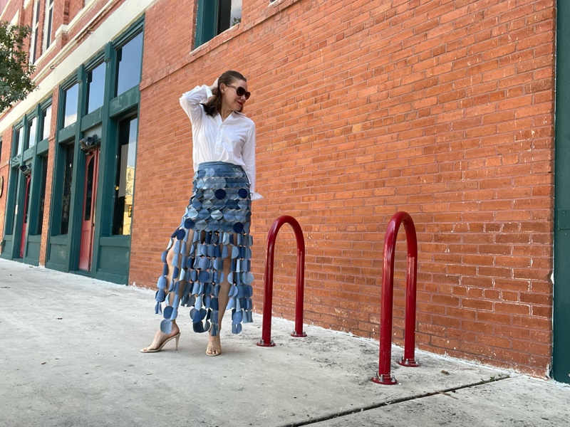 a woman in a denim skirt made of circles with a white button down and nude heels