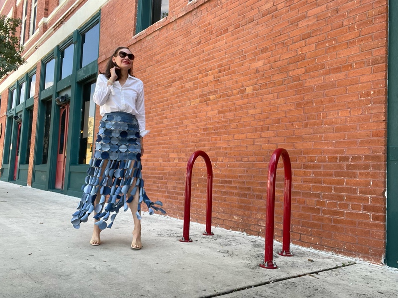 a woman in a denim skirt made of circles with a white button down and nude heels
