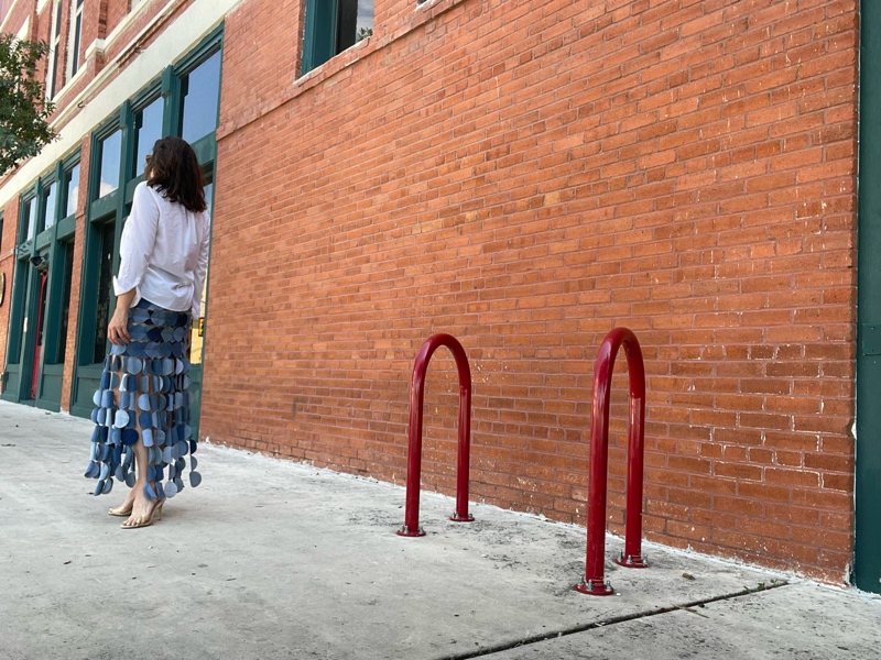 a woman in a denim skirt made of circle, a white button down and a nude heel