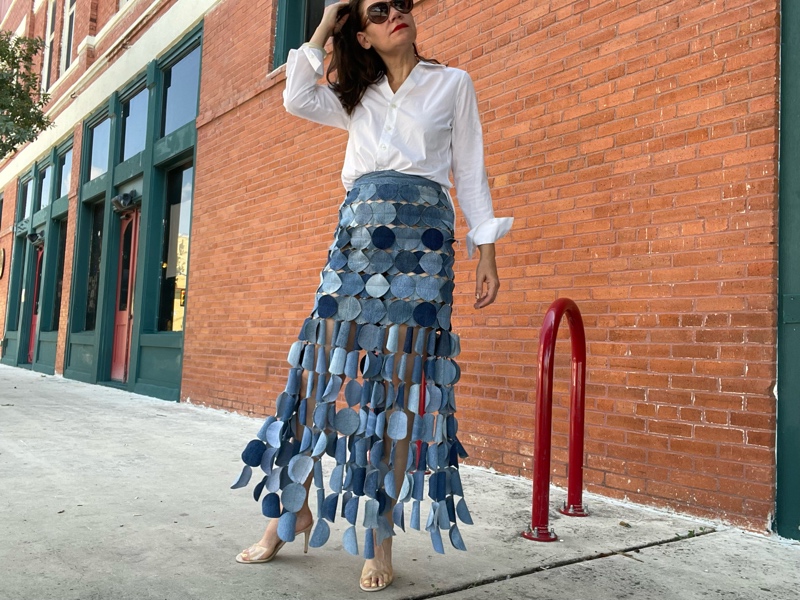 a woman in a denim skirt made of circle, a white button down and a nude heel