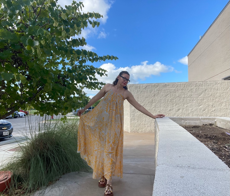 a woman in a blue and gold maxi dress with brown suede platforms