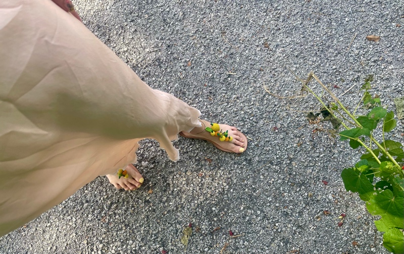 a woman in a vintage peach night gown with flat sandals with fruit charms