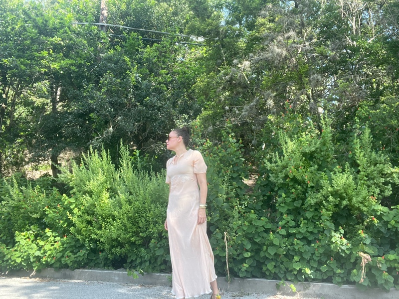 a woman in a vintage peach night gown with flat sandals with fruit charms