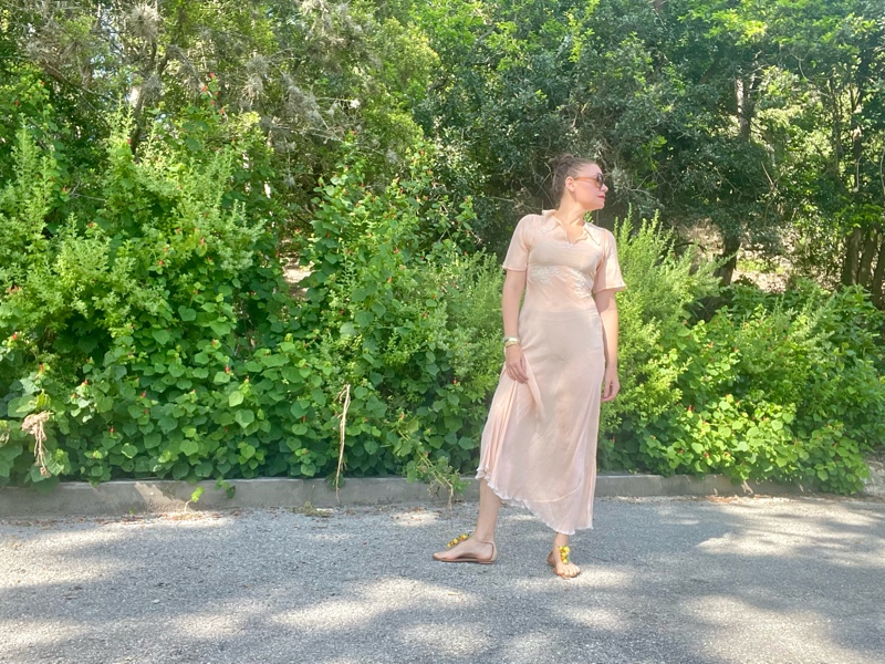 a woman in a vintage peach night gown with flat sandals with fruit charms