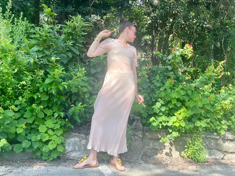 a woman in a vintage peach night gown with flat sandals with fruit charms