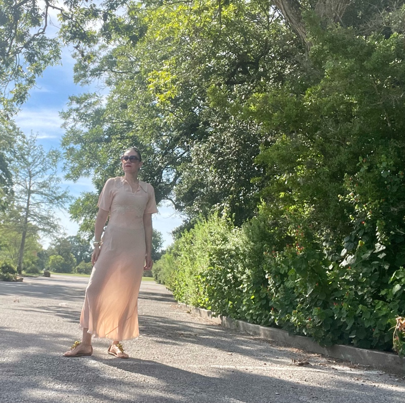 a woman in a vintage peach night gown with flat sandals with fruit charms