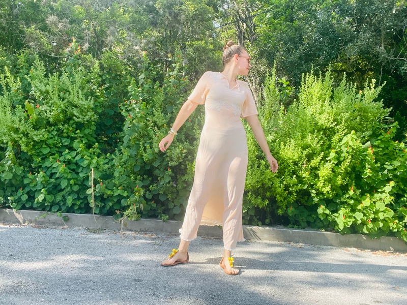 a woman in a vintage peach night gown with flat sandals with fruit charms