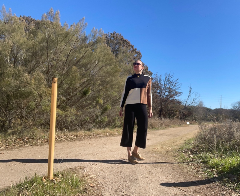 A woman in black, camel and white color block turtleneck sweater and pants with mesh leather sneakers 