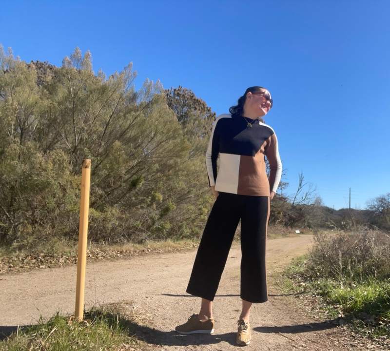 A woman in black, camel and white color block turtleneck sweater and pants with mesh leather sneakers 