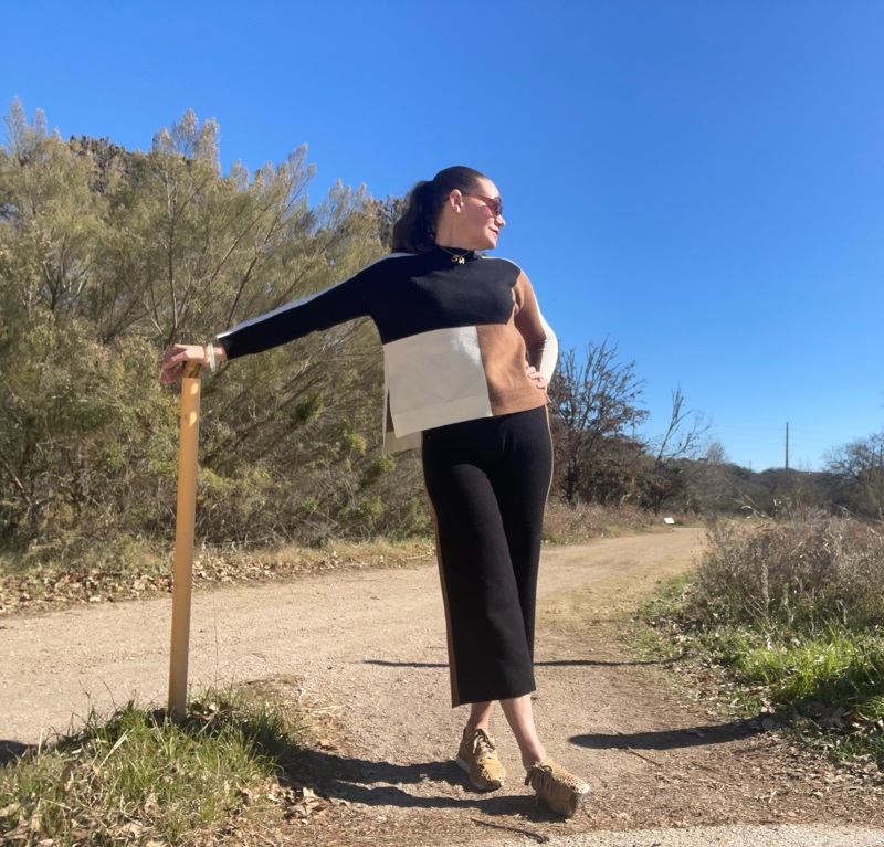 A woman in black, camel and white color block turtleneck sweater and pants with mesh leather sneakers 