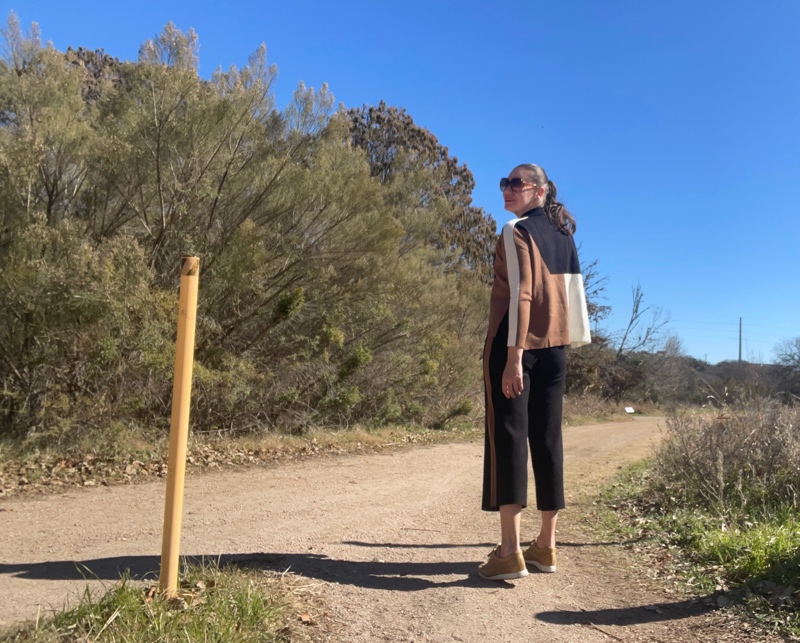 A woman in black, camel and white color block turtleneck sweater and pants with mesh leather sneakers 