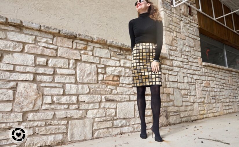 a woman in a black turtleneck, hose and heels and a golden tile skirt